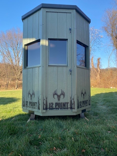 6-Octagon-1 - Ideal Land Management | Forestry mowing & mulching, food plots, hunting blinds Octagonal green hunting blind on stilts in a grassy field, with three windows and a door, and '12 POINT' branding along the base.